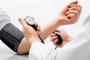 Doctor measuring blood pressure - studio shot on white background