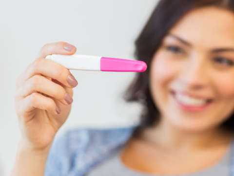 Woman smiling holding pregnancy test